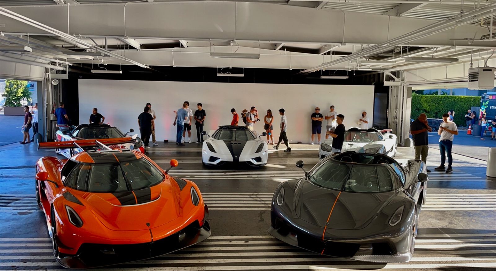 Visitors gathered around hypercars on display at an automotive showcase