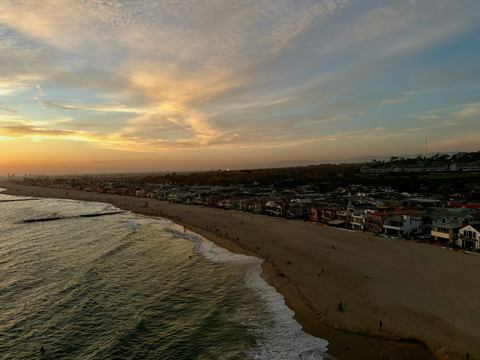 Aerial of a beach-town shoreline under a golden sunset