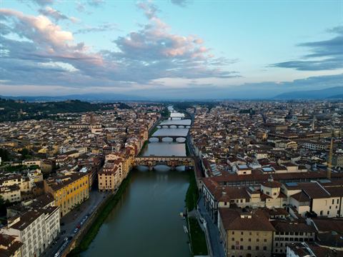 Aerial view of the Arno River and Ponte Vecchio winding through Florence at dusk