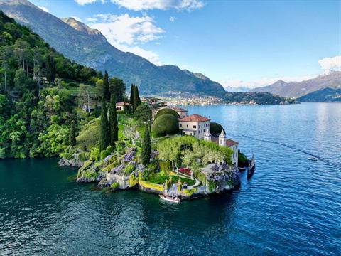 Wooded promontory and villa gardens on the deep blue water of Lake Como, from above