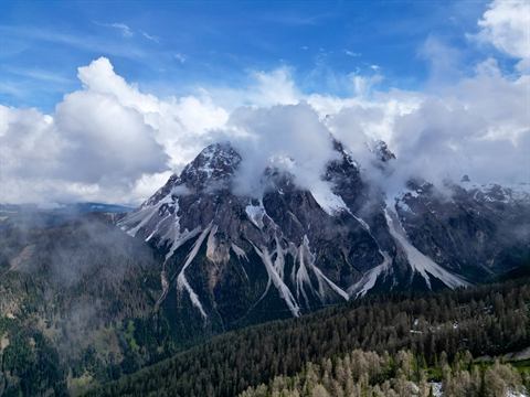 Jagged Dolomite peaks wrapped in cloud, seen from drone altitude