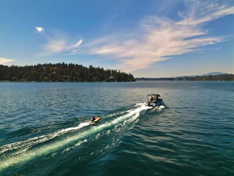 Boat carving a white wake across a mountain lake, surfer in tow