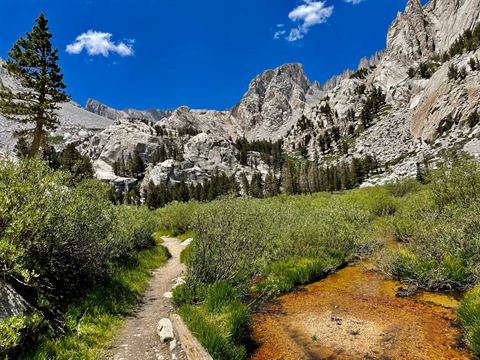 High-country trail winding through Sierra granite, a dog trotting ahead