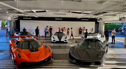 Visitors gathered around hypercars on display at an automotive showcase