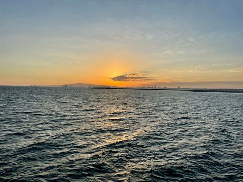 Setting sun sinking toward the ocean beyond gentle swells