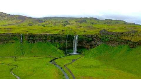 Waterfalls spilling over mossy green cliffs in Iceland